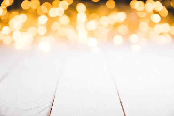 Magische verschwommene Lichter auf weißer Holzoberfläche, weihnachtliche Textur — Stockfoto