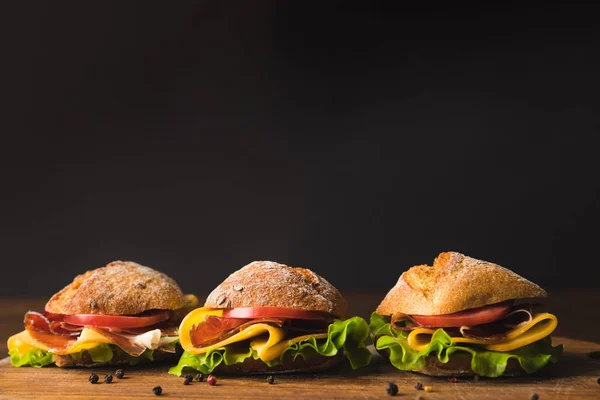 Sandwichs au fromage et légumes sur planche de bois au poivre éparpillé — Photo de stock