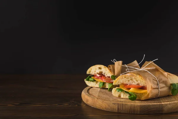 Two cooked delicious panini with vegetables on wooden board on table — Stock Photo