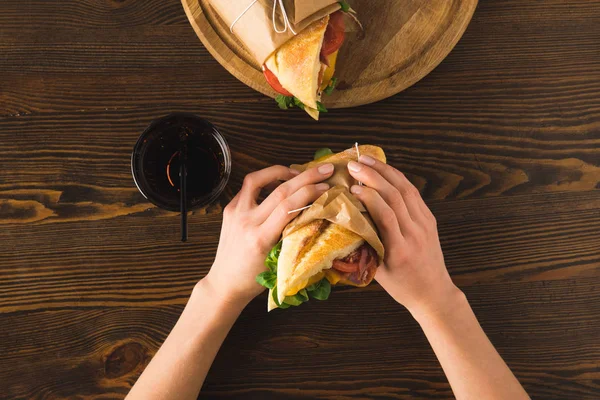 Cropped image of woman holding sandwich in hands — Stock Photo