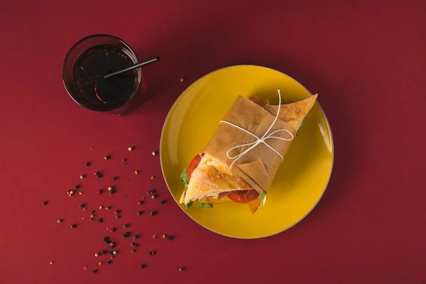 Вид сверху на сэндвич на тарелке и стакан колы на столе — Stock Photo