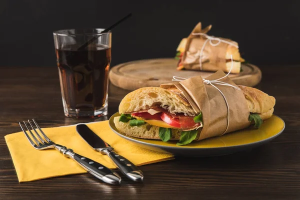 Cooked panini on yellow plate and knife with fork — Stock Photo