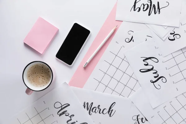 Flat lay com calendário, smartphone, xícara de café e notas pegajosas isoladas em branco — Fotografia de Stock