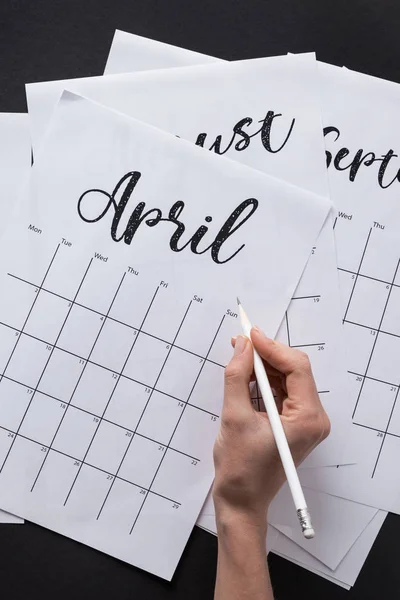 Partial view of woman making notes in calendar isolated on black — Stock Photo