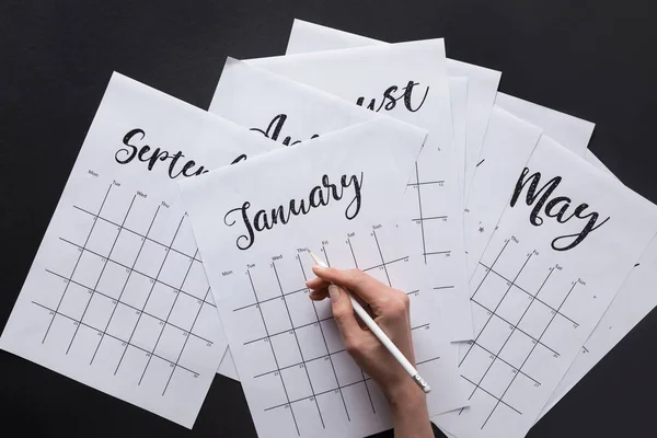 Vista parcial de la mujer haciendo notas en el calendario aislado en negro - foto de stock