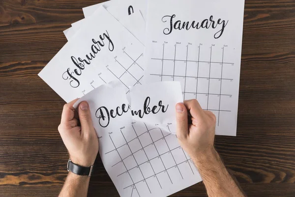 Cropped shot of man tearing calendar on wooden tabletop — Stock Photo