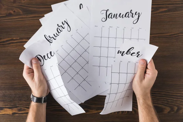 Cropped shot of man tearing calendar on wooden tabletop — Stock Photo