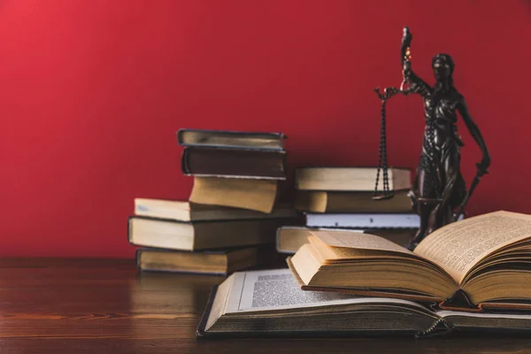 Aufgeschlagene juristische Bücher mit Dame Gerechtigkeitsstatue auf Holztisch, Gesetzeskonzept — Stockfoto