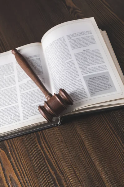 Opened juridical book with hammer on wooden table, law concept — Stock Photo