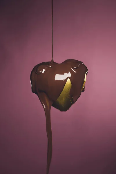 Caramelo en forma de corazón en envoltura de oro con chocolate líquido aislado en rosa — Stock Photo