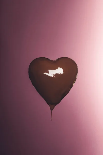 Caramelo en forma de corazón con chocolate líquido aislado en rosa - foto de stock