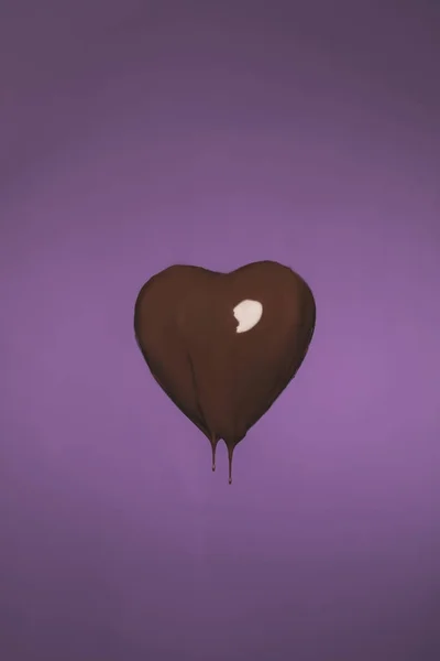 Heart shaped candy with liquid chocolate isolated on purple — Stock Photo