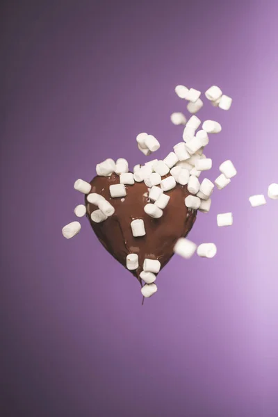 Chocolate heart shaped candy with falling marshmallow isolated on purple — Stock Photo