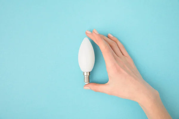 Visão parcial da mulher segurando lâmpada na mão isolado em azul — Fotografia de Stock