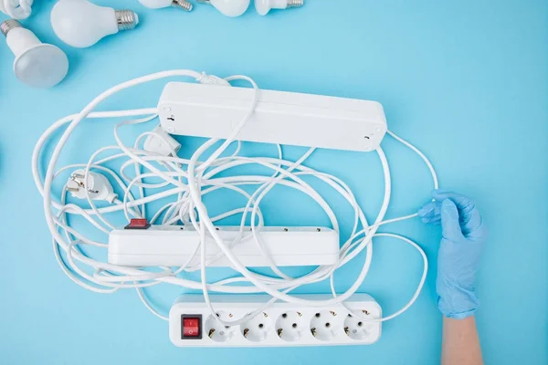 Partial view of female hand in protective gloves and extension cords isolated on blue — Stock Photo