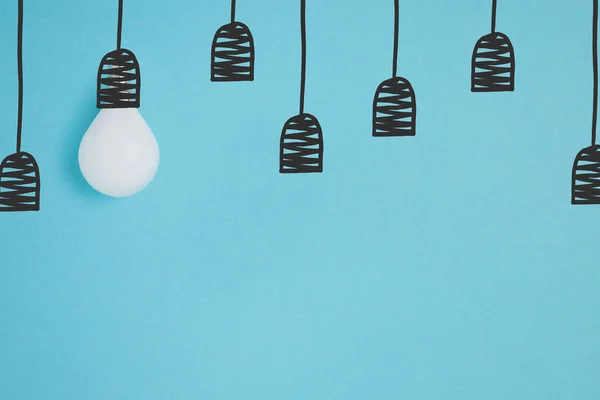 Flat lay with white light bulb pretending hanging on string isolated on blue — Stock Photo