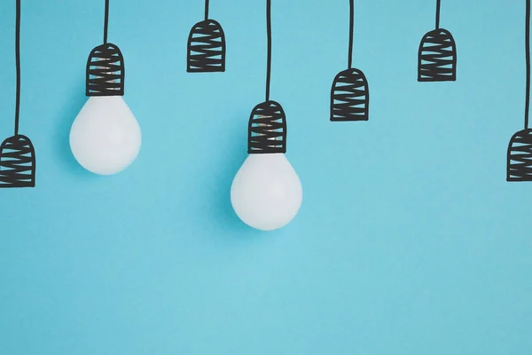 Close up view of white lamps pretending hanging on lamp holders isolated on blue — Stock Photo