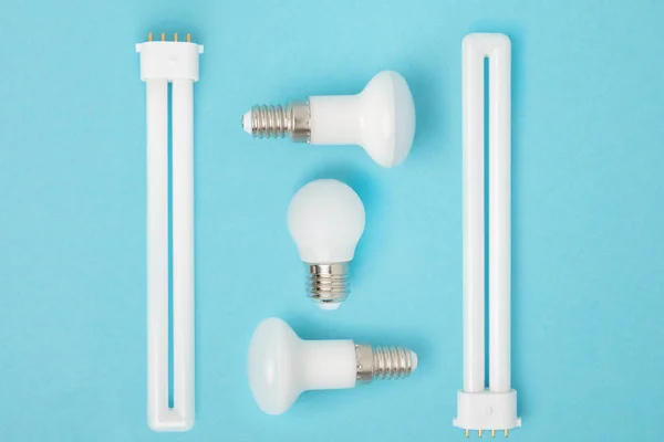 Leigos planos com dispostas várias lâmpadas isoladas em azul — Fotografia de Stock