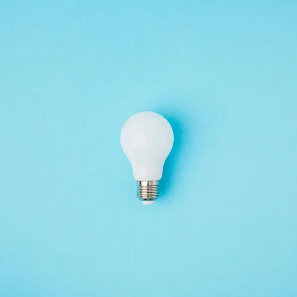 Close up view of white light bulb isolated on blue — Stock Photo