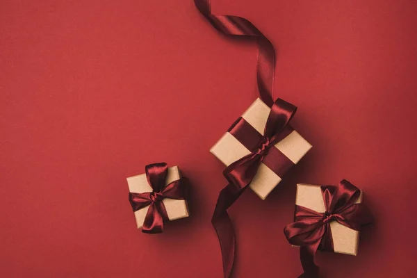 Flat lay with arrangement of gifts decorated with ribbons isolated on red — Stock Photo