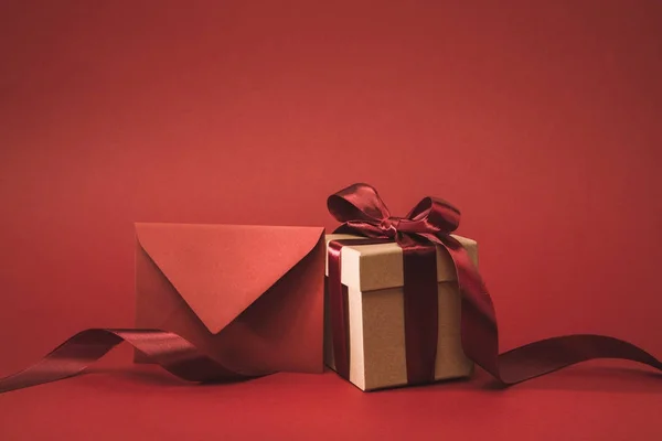 Close up view of empty envelope and present with ribbon isolated on red — Stock Photo