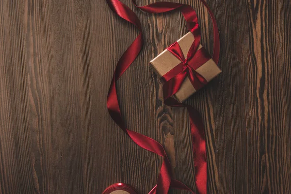 Tendido plano con presente y cinta roja en la mesa de madera — Stock Photo