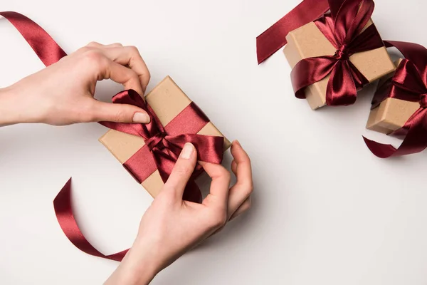 Vista parcial de la mujer atando cinta en caja de regalo aislado en blanco - foto de stock