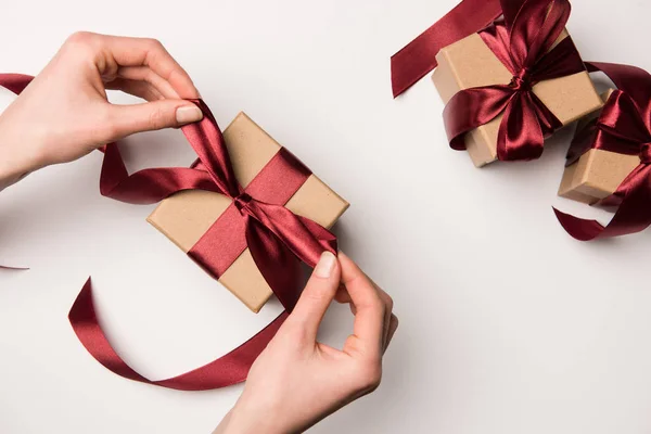 Partial view of woman tying ribbon on gift box isolated on white — Stock Photo