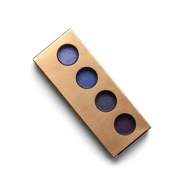Top view of golden container with different shaded purple eye shadows on white — Stock Photo