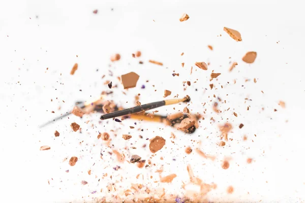 Crushed cosmetic powder with makeup brushes falling isolated on white — Stock Photo