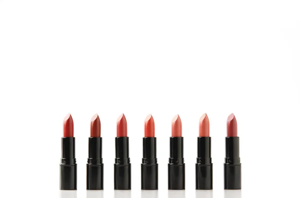 Row of lipsticks of various shades in black tubes isolated on white — Stock Photo