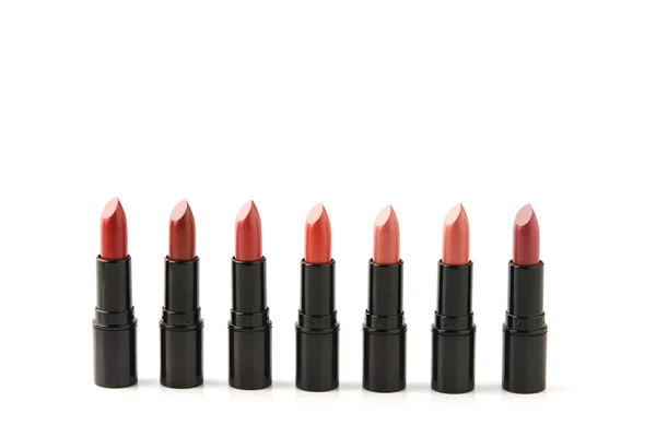 Fila de lápices labiales rojos de varios tonos aislados en blanco - foto de stock