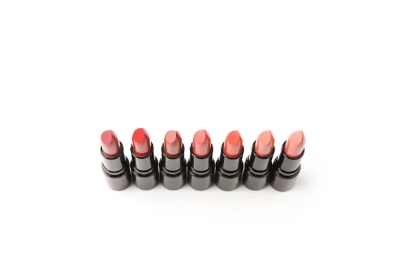 Vue grand angle de la rangée de différents rouges à lèvres ombragés isolés sur blanc — Photo de stock