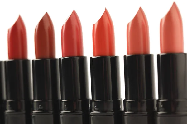Primer plano de la fila de lápices labiales rojos de varios tonos aislados en blanco - foto de stock