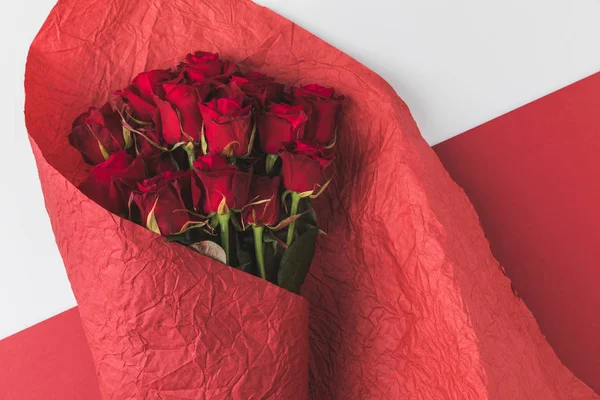 Top view of bouquet of roses in red wrapping paper isolated on white — Stock Photo