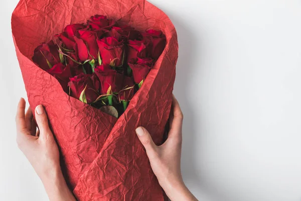 Partial view of woman holding bouquet of red roses in wrapping paper for st valentines day isolated on white — Stock Photo