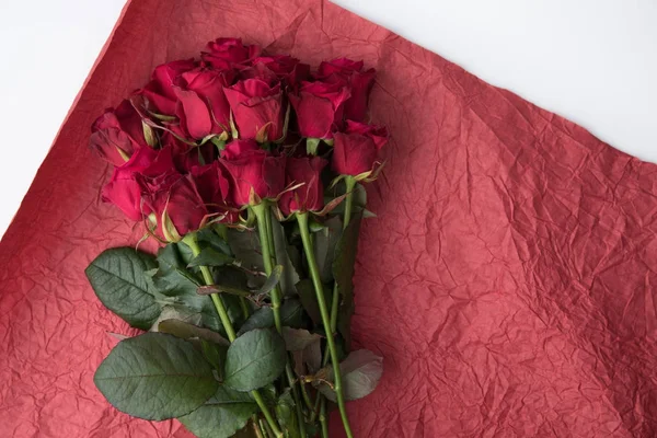 Vista superior del ramo de rosas sobre papel de regalo rojo aislado sobre blanco - foto de stock