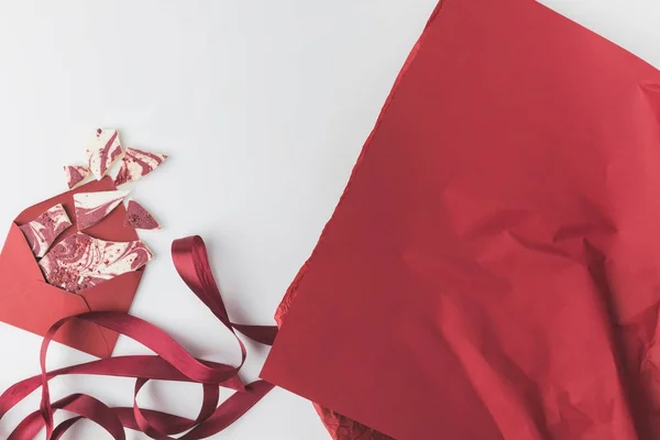 Vue du dessus du papier d'emballage rouge arrangé et enveloppe avec dessert pour la Saint Valentin isolé sur blanc — Photo de stock