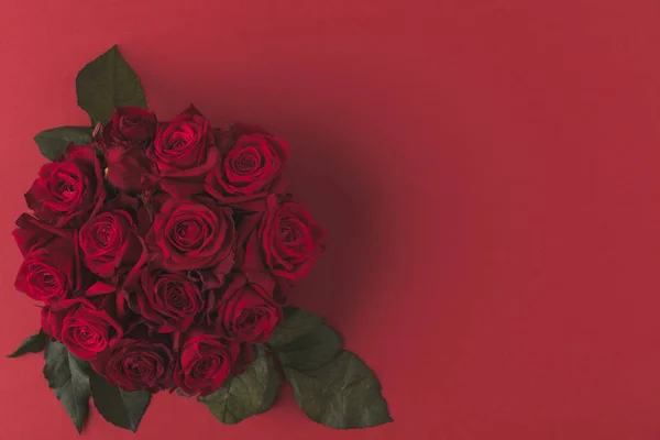 Vue du haut du bouquet de roses rouges aux feuilles vertes isolées sur rouge — Photo de stock