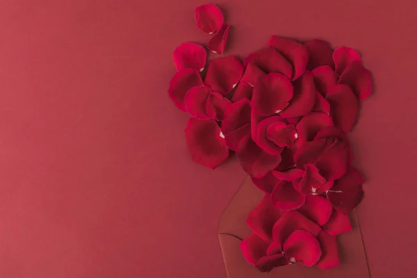 Top view of roses petals and envelope isolated on red — Stock Photo