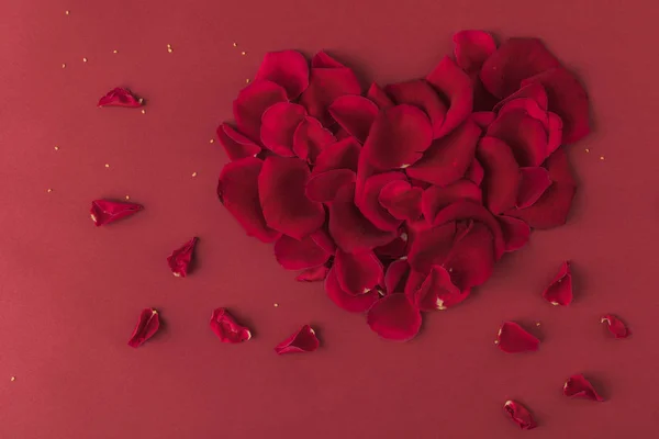 Vista superior del corazón hecha de pétalos de rosas aislados en rojo - foto de stock