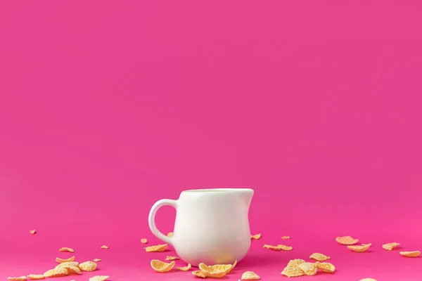 Close-up view of jug with milk and crunchy corn flakes on pink — Stock Photo