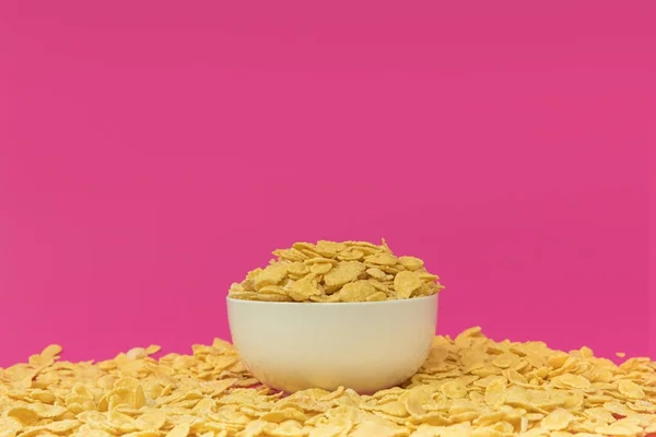 Close-up view of white bowl with tasty crispy corn flakes isolated on pink — Stock Photo