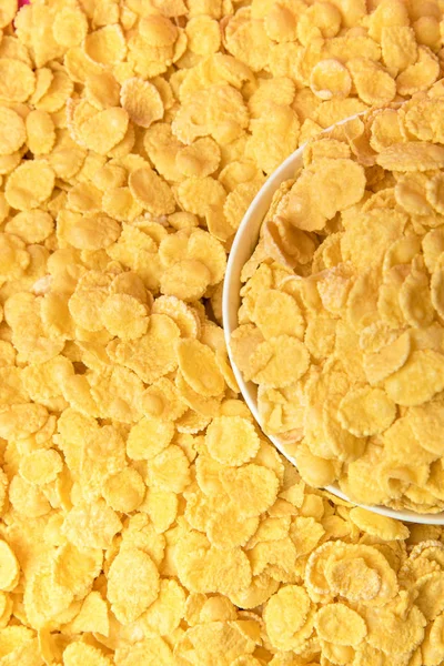 Vista superior de sabrosos copos de maíz crujientes y tazón blanco - foto de stock