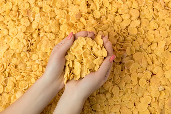 Вид сверху на женские руки с хрустящими вкусными кукурузными хлопьями — стоковое фото