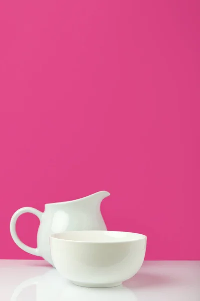 Vista close-up de tigela branca vazia e jarro em rosa — Fotografia de Stock