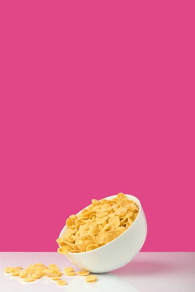 Ciotola bianca piena di fiocchi di mais gustosi sani su rosa — Foto stock