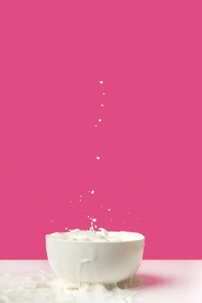 Tigela cheia de leite orgânico saudável fresco e salpicos com gotas em rosa — Fotografia de Stock
