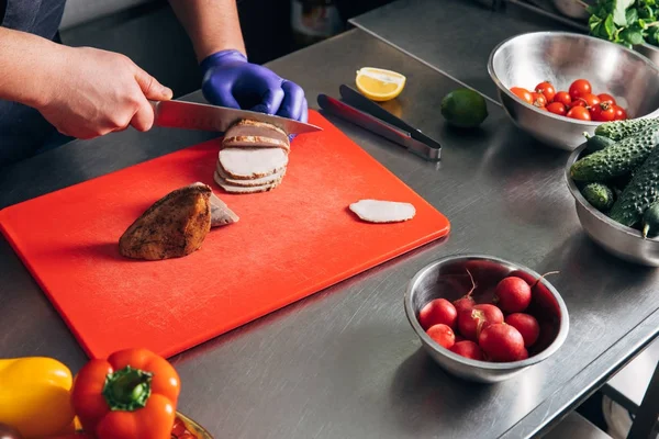 Tiro de chef rebanando carne en la cocina - foto de stock