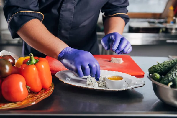 Abgeschnittene Aufnahme von Koch, der Käsestücke auf den Teller legt — Stockfoto